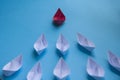 Leadership Concept - Red color paper ship origami leading the rest of the white paper ship on blue cover background Royalty Free Stock Photo