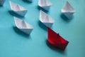 Leadership Concept - Red color paper ship origami leading the rest of the white paper ship on blue cover background Royalty Free Stock Photo