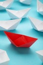 Leadership concept. Red leader paper ship leading among white on blue background. Vertical photo Royalty Free Stock Photo