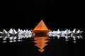 Leadership concept. White paper boats led by orange one. isolated on black Royalty Free Stock Photo