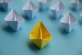 Leadership Concept - Yellow color paper ship origami leading the rest of the white paper ship on blue cover background Royalty Free Stock Photo