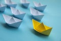 Leadership Concept - Yellow color paper ship origami leading the rest of the white paper ship on blue cover background Royalty Free Stock Photo