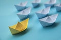 Leadership Concept - Yellow color paper ship origami leading the rest of the white paper ship on blue cover background Royalty Free Stock Photo
