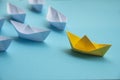 Leadership Concept - Yellow color paper ship origami leading the rest of the white paper ship on blue cover background Royalty Free Stock Photo