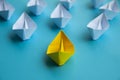 Leadership Concept - Yellow color paper ship origami leading the rest of the white paper ship on blue cover background Royalty Free Stock Photo