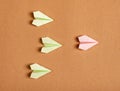 Leadership. Green origami planes and outstanding pink one flying ahead on brown background. Guidance, authority or
