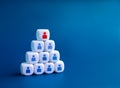 Red person icon on the top among of many blue people symbol on white blocks building as a pyramid shape. Royalty Free Stock Photo