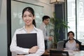 Leadership young Asian business woman standing and smiling with colleage in meeting room background. Royalty Free Stock Photo