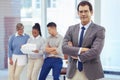 Leading his team through his plan. a businessman standing with her arms crossed in the boardroom with her colleagues in Royalty Free Stock Photo