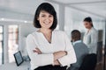 Leading my team to success. an attractive young businesswoman standing with her arms folded while colleagues works Royalty Free Stock Photo
