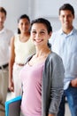 She leads by example. Portrait of a beautiful young businesswoman smiling at you with her team blurred in the background Royalty Free Stock Photo