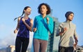 She leads this pack. three young joggers out for a run in the city.