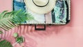 Leaf of fern, tropical detox water and open suitcase with clothes on pastel pink. Top view with copy space. Summer concept travel. Royalty Free Stock Photo