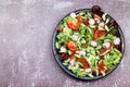 Leaf lettuce with cherry tomatoes, green onions, garlic, bell pepper and radish in a dark plate on a dark background