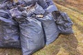 Leaf removal. Black plastic bags with last year's dry leaves on the lawn in the park Royalty Free Stock Photo