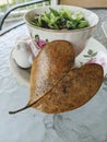 A leaf shaped like a heart in front of a tea cup.