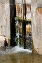 Leaking closed old partially rusted metal river dam gates covered with moss and dirt