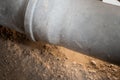 Leaking plastic sewage pipe in an old apartment, visible open hole with removed parquet, sand and buckets around, exposed drain