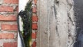 Leaking water mains covered with green moss against a red brick background on a sunny day