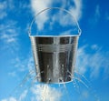 Leaky bucket with water against sky Royalty Free Stock Photo