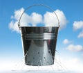 Leaky bucket with water against sky Royalty Free Stock Photo