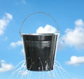 Leaky bucket with water against sky Royalty Free Stock Photo