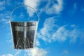 Leaky bucket with water against sky. Space for text Royalty Free Stock Photo