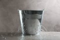 Leaky bucket with water on table against grey background Royalty Free Stock Photo