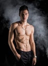 Lean athletic shirtless young man standing on dark background Royalty Free Stock Photo