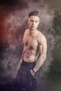 Lean athletic shirtless young man standing on dark background Royalty Free Stock Photo