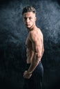 Lean athletic shirtless young man standing on dark background Royalty Free Stock Photo