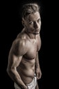 Lean athletic shirtless young man standing on dark background Royalty Free Stock Photo