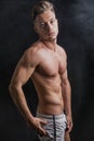 Lean athletic shirtless young man standing on dark background Royalty Free Stock Photo