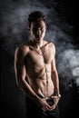 Lean athletic shirtless young man standing on dark background Royalty Free Stock Photo