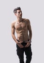 Lean athletic shirtless young man standing on light background