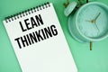 Lean Thinking text with alarm clock flat lay on green background Royalty Free Stock Photo