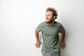 Leaned on the wall and looking sideways handsome young man with curly hair in olive t-shirt isolated on white background Royalty Free Stock Photo