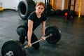 Leaning on the barbell. On the floor. Beautiful strong woman is in the gym