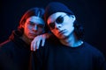 Leaning on the brother. Portrait of twins. Studio shot in dark studio with neon light Royalty Free Stock Photo