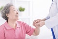leaning forward to smiling elderly holding her hand in palms. Woman caretaker in white coat supporting encouraging old person Royalty Free Stock Photo