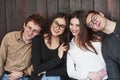 Leaning to each other. Youth stands against black wooden wall. Group of friends spending time together