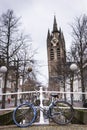 The leaning tower of the old church in Delft. In front a bike leaning against the railing of