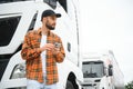 Leaning by the vehicle and using phone. Young truck driver is at daytime Royalty Free Stock Photo