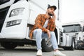 Leaning by the vehicle and using phone. Young truck driver is at daytime Royalty Free Stock Photo