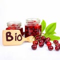 ?lear glass jar filled with cherry jam and berries sits next to wooden sign bearing word Bio.