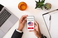 Learn Business English online. Young man holding smartphone with educational application over table, top view