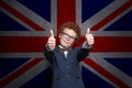 Learn English concept. Child boy student having fun and showing thumb up on the UK flag background Royalty Free Stock Photo