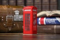 Learn English concept. Red telephone booth on backgrpund of english course textbook and vintage suitcase Royalty Free Stock Photo
