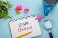 Learn English Text written on notebook page, red pencil and coffee cup. Office desk table top view Royalty Free Stock Photo