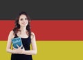 Learn German language. Attractive young woman holding phrasebook against the Germany flag background Royalty Free Stock Photo